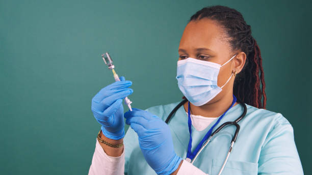 Black female doctor draws up injection, vaccine vial, needle, IVF treatment stock photo