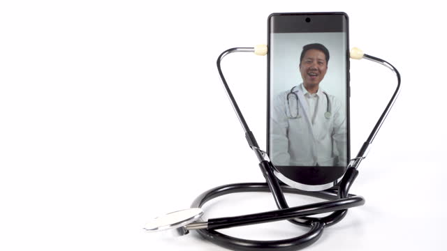 A doctor is on a phone with a stethoscope around his neck.