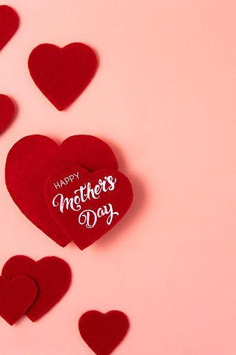 Mother’s day concept with heart shaped felt textile and handwriting text on pink background