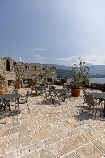 Budva, Montenegro - June 28, 2023: Medieval fortress of St. Mary, also known as the Citadel. View from the outside restaurant to the Adratic Sea