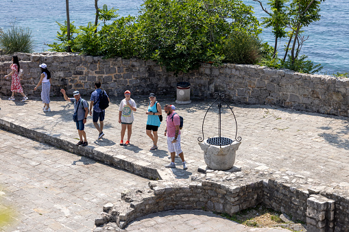 Budva, Montenegro - June 28, 2023: Tourists on the terrace of dedieval fortress of St. Mary, also known as the Citadel. View of the courtyard with the historic well