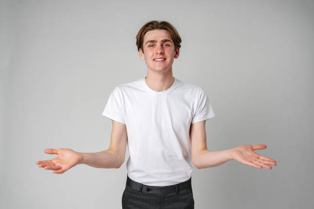 istock Young Man in White T-Shirt Gesturing With Open Arms Against a Plain Background 2132822430
