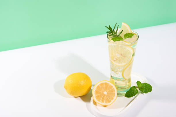 istock Cool freshly made lemonade, ice cubes and lemon fruits on white table background. 2132826623