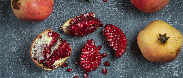 Ripe pomegranate fruit with beautiful red seeds, sweet, delicious, healthy, on a gray background.