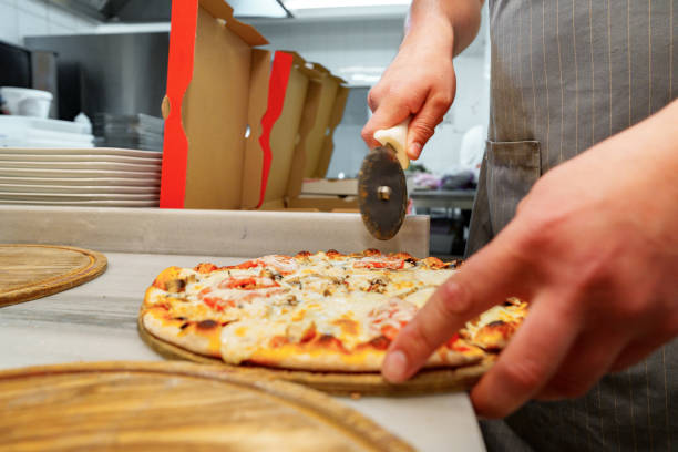 istock Chef Cutting Freshly Baked Pizza in a Commercial Kitchen Setting 2132872202