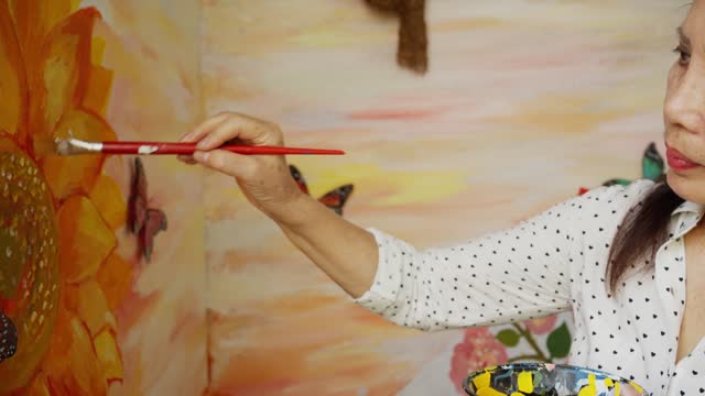 Mature woman painting a colorful mural at home using a brush