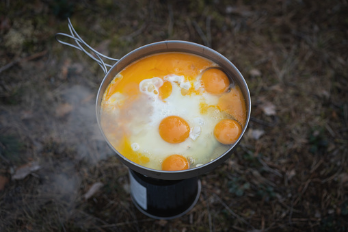 Cooking outdoors at a campsite using gas. Scrambled eggs in a frying pan. Close up photo