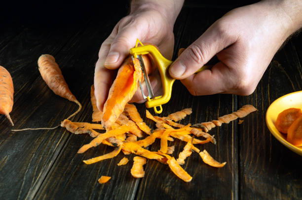 istock Chef hands peel carrots with a vegetable peeler on the kitchen table in a restaurant. Preparing a vegetable dish for breakfast 2132925665