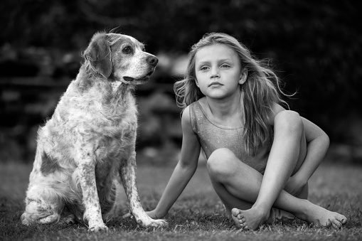 portrait of a little girl sitting on the grass with a dog