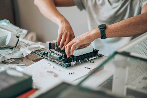 Component Connection : A close-up of hands meticulously assembling a desktop's motherboard, symbolizing the confluence of technology and manual expertise