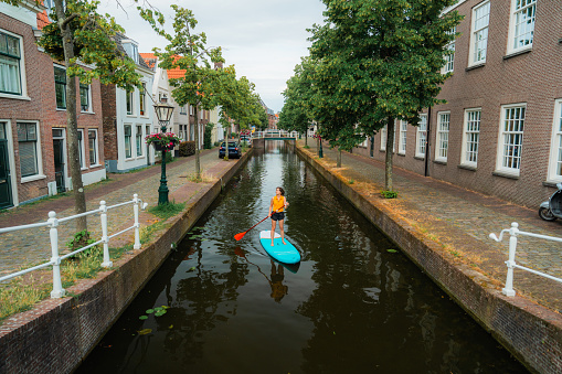 Woman SUP boarding on canal in the Netherlands  in summer