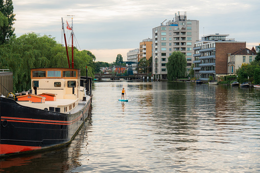 Woman SUP boarding on canal in the Netherlands  in summer