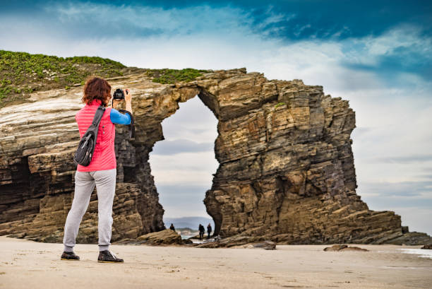 istock Woman with camera at Cathedral Beach, Galicia Spain. 2133046849