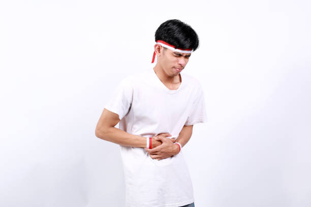istock Young asian boy with red white ribbon celebrating Indonesia independence day while holding his stomachache, stomachache concept 2133068496