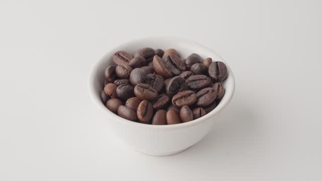 Close-up of hand holding white cup with roasted coffee beans