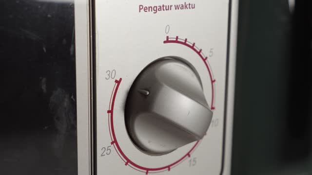 Hand Turning Manually The Knob Of Electric Microwave Oven, Close Up