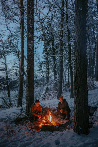 Men hiking in the winter. Warming up by a burning campfire