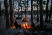 Winter holidays in the snow. Two men warming up by the bonfire