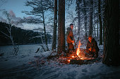 Winter holidays in the snow. Two men warming up by the fire