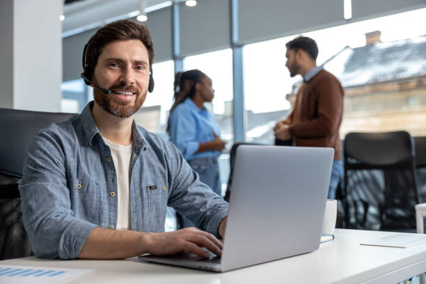 istock Smiling man working in call center on phone with headset 2133104303