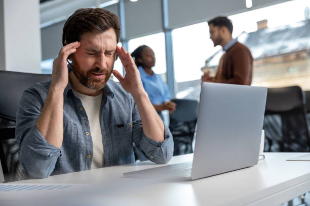 istock Exhausted man call center operator suffering headache at workplace 2133104304