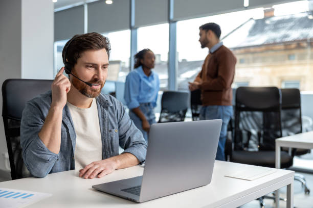 istock Smiling man working in call center on phone with headset 2133104306