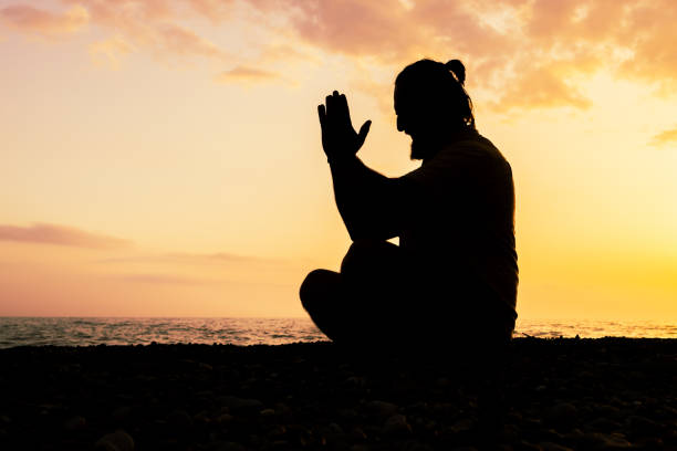 istock A man is sitting on the beach and praying 2133161051
