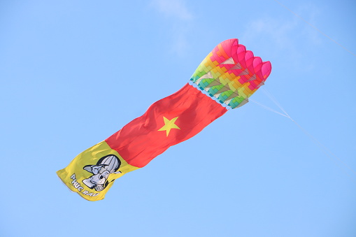 Can Tho, Vietnam - March 23, 2024: Colorful flag kite flying in the clear blue sky in sunny summer day at Mekong Delta Vietnam. Happy childhood moments.