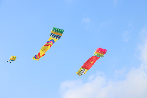 Can Tho, Vietnam - March 23, 2024: Colorful kites flying in the clear blue sky in sunny summer day at Mekong Delta Vietnam. Happy childhood moments.