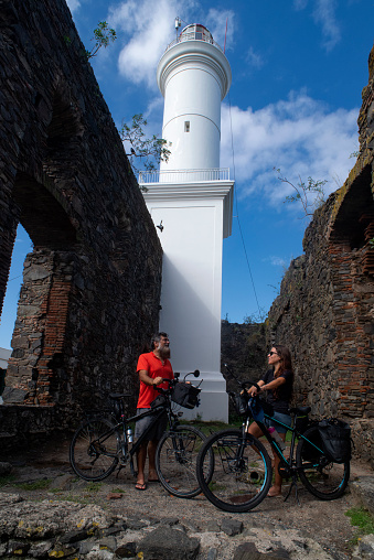 Couple with tourist bicycles at the lighthouse located in the historic center of Colonia del Sacramento in Uruguay
