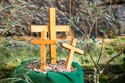 An Easter garden made up of potted plants and three wooden crosses representing the three crosses of Good Friday outside a church.