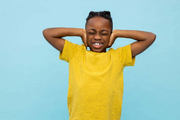 istock Boy in yellow tshirt looking stressed and closing ears with his hands 2133190744