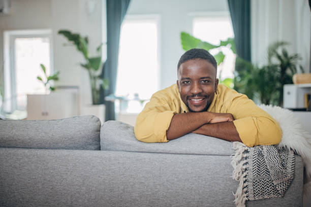istock Smiling man relaxing on couch at home 2133218491