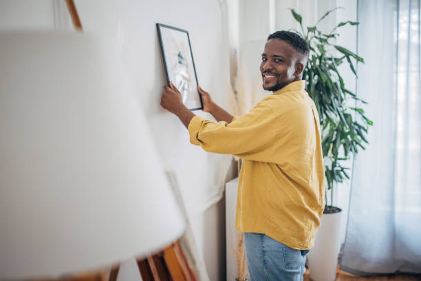 istock Smiling man hanging picture on wall at home 2133223878