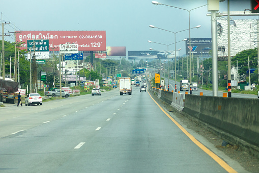 Driving on highway in Amphoe Pak Chong in Nakhon Ratchassima province in Thailand. A few traffic is ruling and huge banners are alongside highway including gas stations