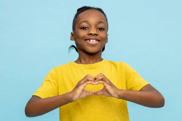 Photo of Friendly African American little boy showing heart made with hands