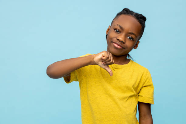недовольный афроамериканский мальчик показывает большой палец вниз - little boys black african descent american culture стоковые фото и изображения