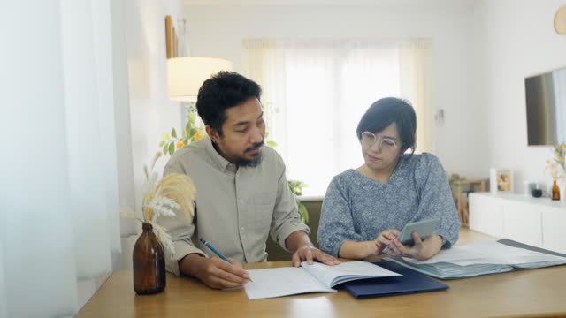 Serious couple talking together, looking at paper bills, checking financial expenses at home.