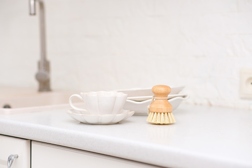 Side view of bamboo dishwashing brushes near sink on table in kitchen. Washing dishes. Home comfort. Eco-friendly kitchenware. Household equipment. Concept of cleanliness. High quality photo