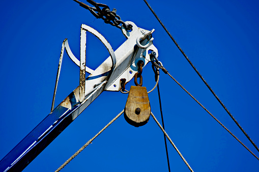 Close-up view of a wheel pulley attached to a fly boom on a commercial fishing trawler.
