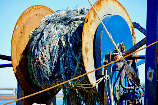 Commercial fishing nets rolled up onto a spool on the back of a commercial fishing trawler.