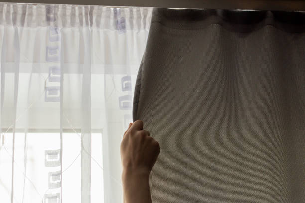 istock A young man opens or closes a gray curtain fabric. 2133368550