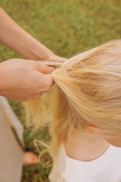 Mother carefully braids her daughter's hair