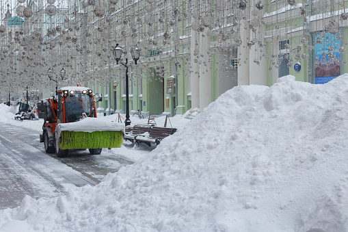 Sweeper brushes the pedestrian area from snow in winter. Moscow, Russia, February 13, 2021.