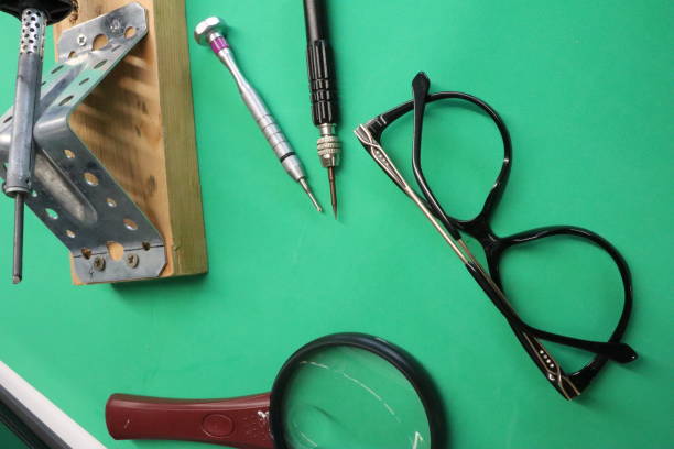 istock Pliers, hand tool, screwdriver, magnifying glass, pen on green surface 2133403853