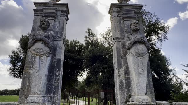 Mammalocchi busts travertine columns with allegorical figures standing at entrance to private villa in Umbria, Italy. Tilt up