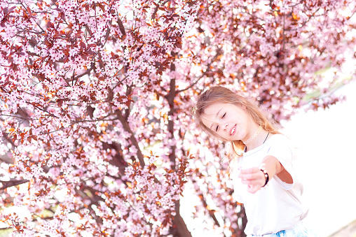 Charming girl in blooming orchard on beautiful spring day