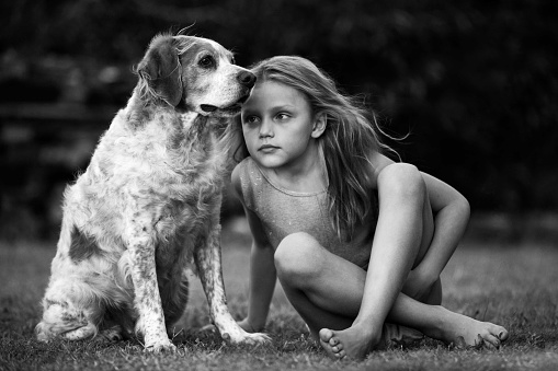 little girl sitting with her dog on the grass