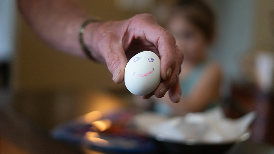 78 year old enjoying coloring Easter eggs with his  great granddaughter