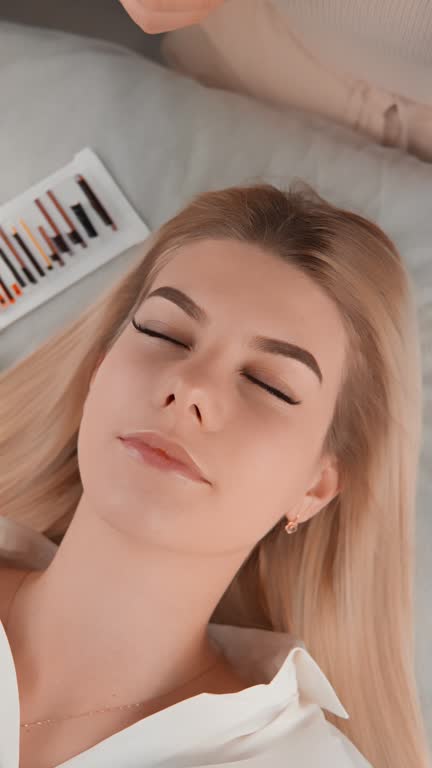 During eyelash extensions and eyeliners in beauty salon this woman transforms her look, giving her eyes more expressive and attractive look. Every moment procedure brings her new sense beauty elegance